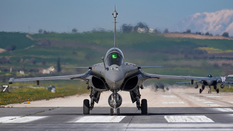 A Dassault Rafale preparing for take-off and generating haze in the process, a second Rafale on the right in the background