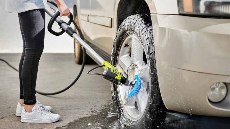 Woman using Ryobi Soap Dispensing Scrubber to clean car tire