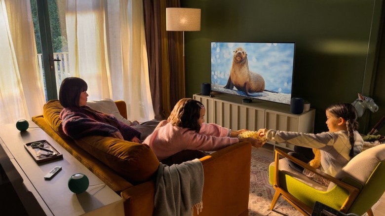 A picture of people watching a show on Apple TV 4K and using HomePod Mini 2 speakers as a home theater setup