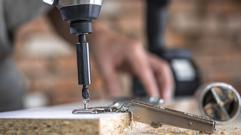 A person using a drill on a screw.