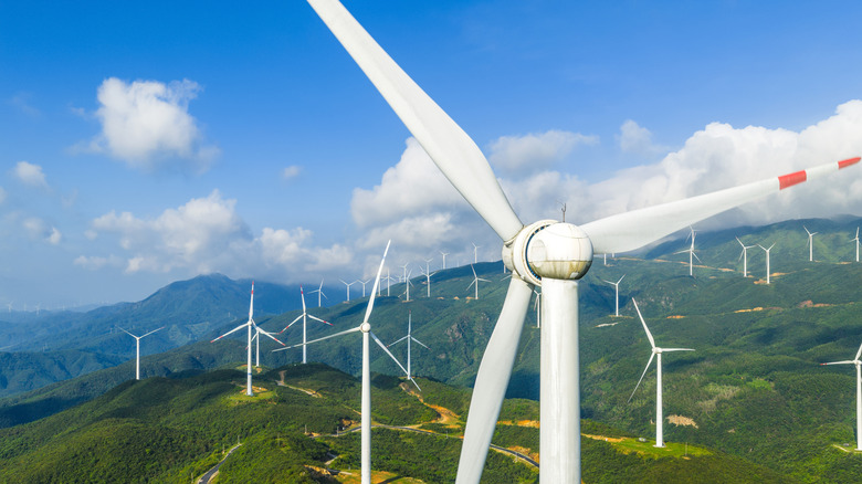 Aerial view of a wind farm with large wind turbines on green mountain