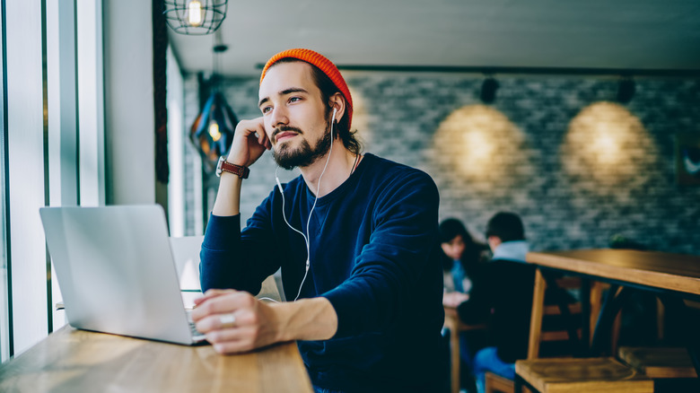 person with laptop headphones cafe
