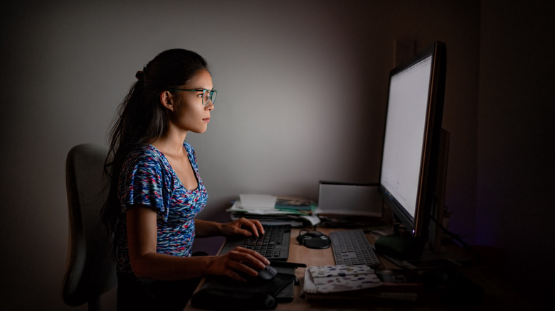 A woman working at a computer in a dark room