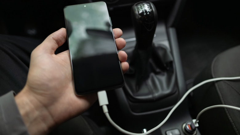 Person charging a phone in their car