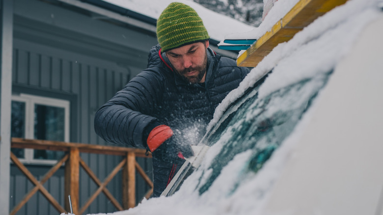 Person scraping ice and snow from their windshield