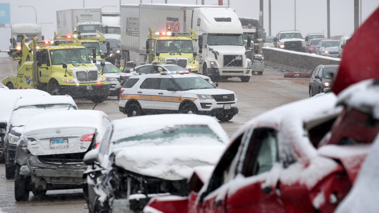 The scene of a multi-car accident on a highway in snow weather with police and emergency vehicles on scene