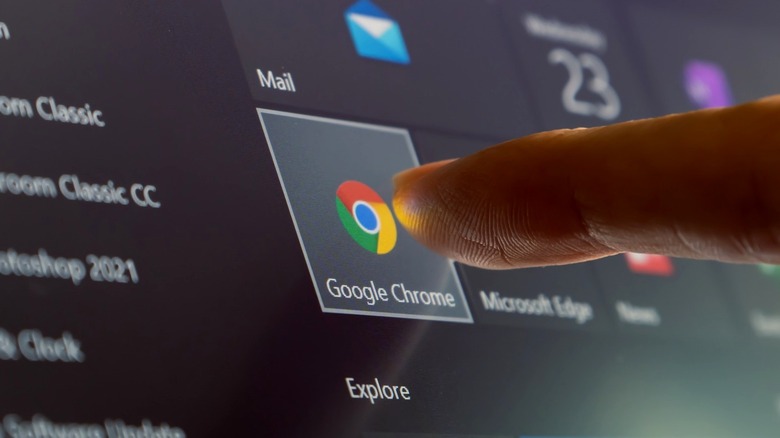 Google Chrome icon on touchscreen with human finger