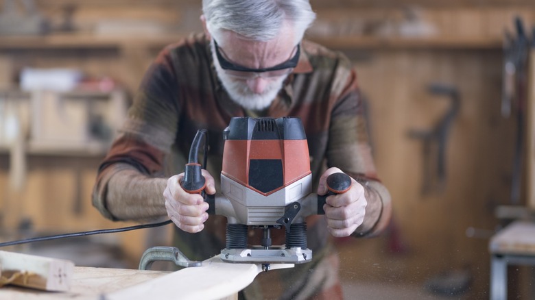 A woodworker using a router to shape a board.