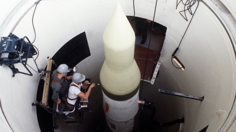 A Minuteman III ICBM being worked on by two men in its launch silo in 1980