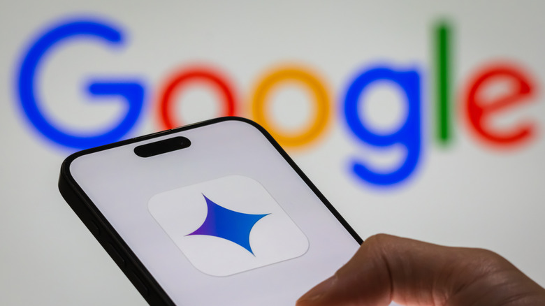 Close-up of a person's hand holding a smartphone displaying the logo of "Gemini," Google's AI-powered model, with the Google logo visible in the background.