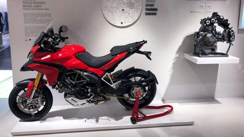 Red Ducati Multistrada on display alongside its engine