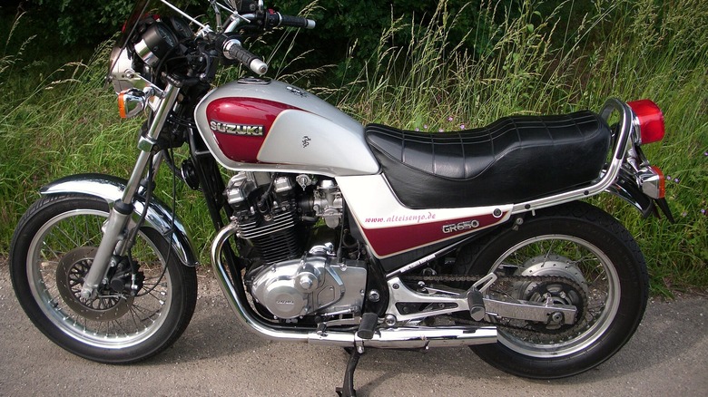 1985 Suzuki 650 Tempter parked in front of weeds and a brick wall