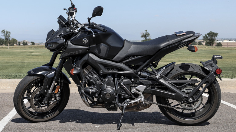 Profile of a black Yamaha MT09 in front of grassy field