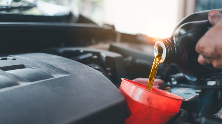 Mechanic pouring fresh oil into a vehicle's oil reservoir