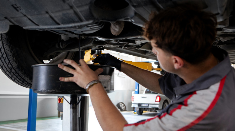 Mechanic draining the oil from a vehicle