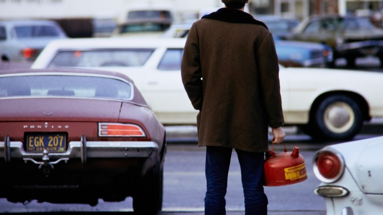 Man holding a red gas can while waiting in a gas line during the 1973 fuel crisis