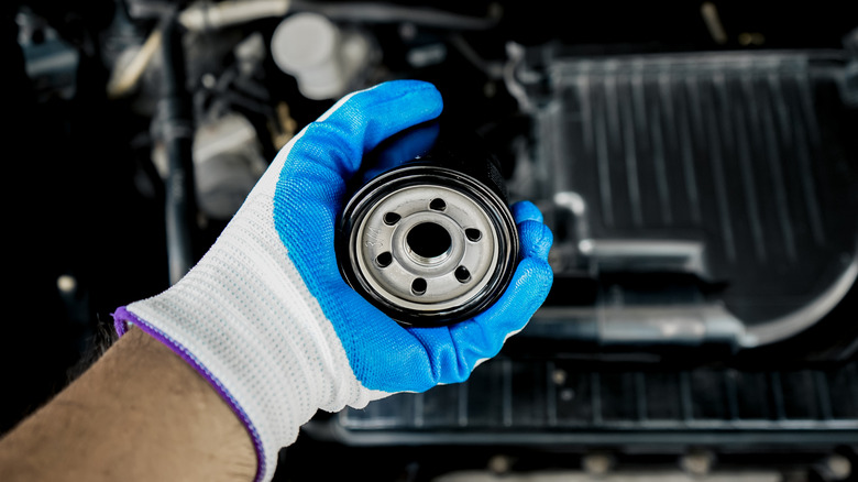 A person holding an oil filter.