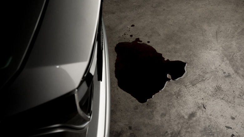 A puddle of oil beside a car.