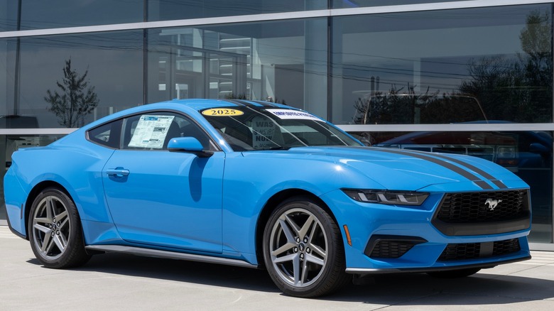 A light blue Ford Mustang on display at a dealership showroom.