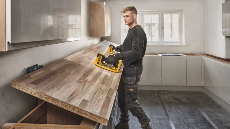 A worker using a 20V Max Grabo Lifter to position a wooden countertop.
