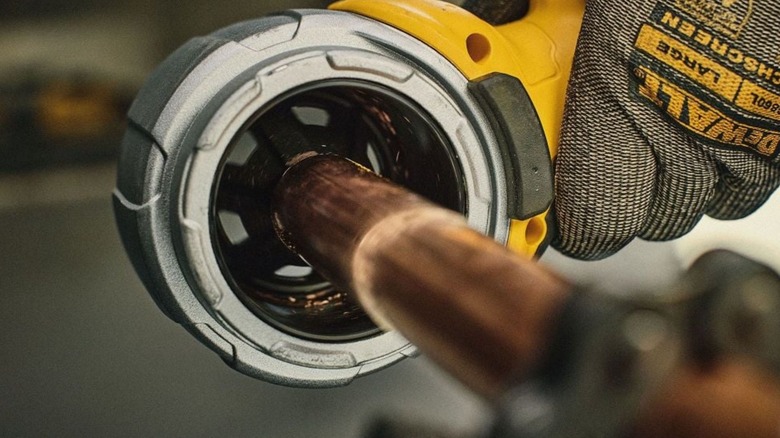 A DeWalt 20V Max Pipe Deburring Tool being used on a length of copper pipe.