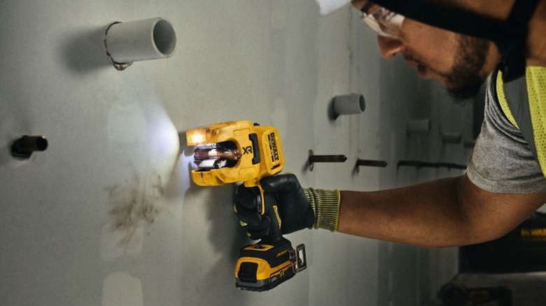 A worker using the DeWalt 20V Max XR 1-¼-Inch Copper Tubing Cutter to trim copper plumbing.