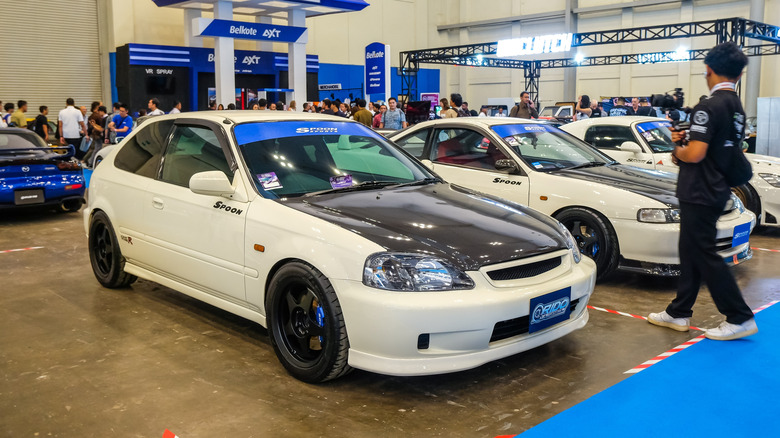 A white EK9 Honda Civic Type R at a tuning show, front 3/4 view