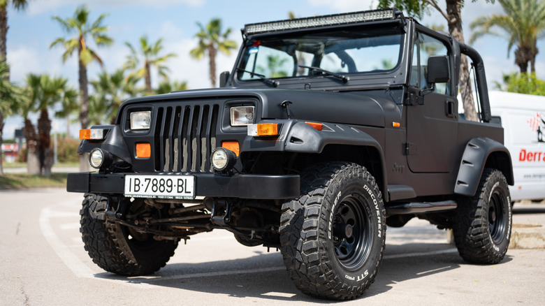 A matte black 1996 Jeep Wrangler with all-terrain tires, front 3/4 view