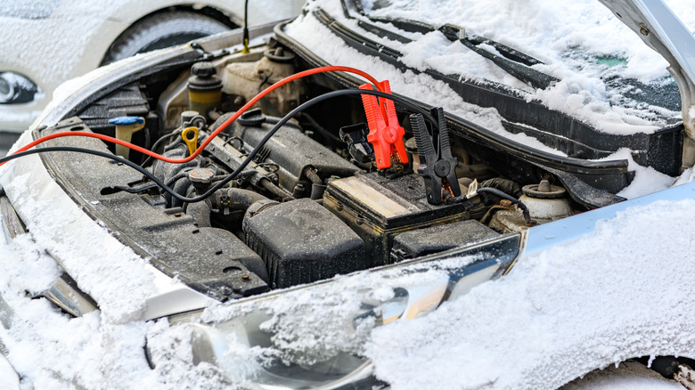 Charging automobile discharged battery by booster jumper cables at winter