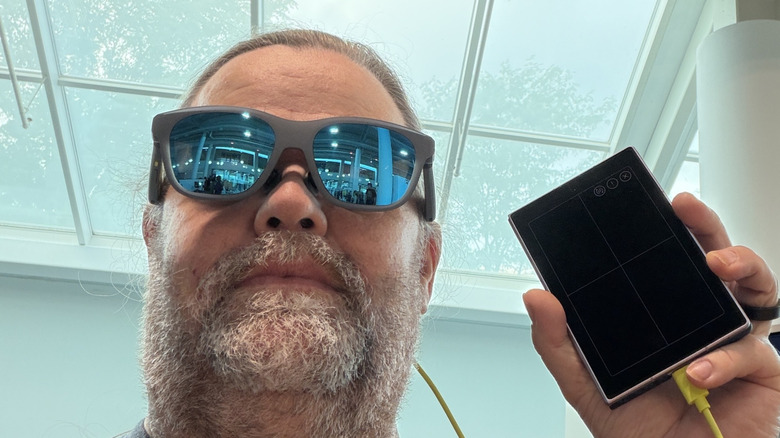 man holding a phone connected to XReal xbx a01+ AR glasses