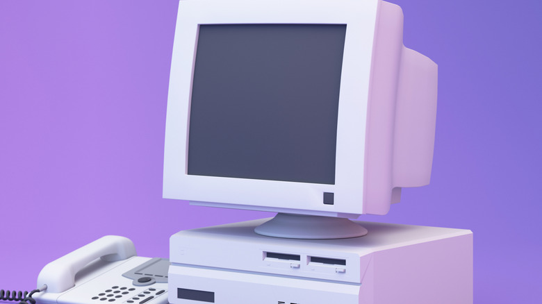 A render of an older PC and phone in front of a purple/pink background