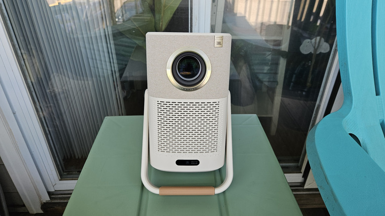 The Yaber T2 Plus Outdoor Projector outside on a green table using its handle as a stand.