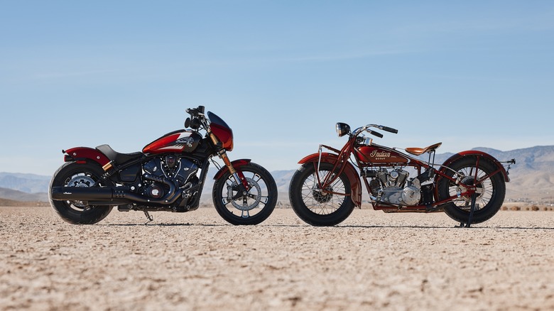 A 2025 Indian 101 Scout faces a 1928 model of the same name in a barren, flat landscape.