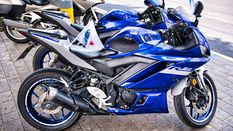 A blue Yamaha R3 on a parking lot, side profile