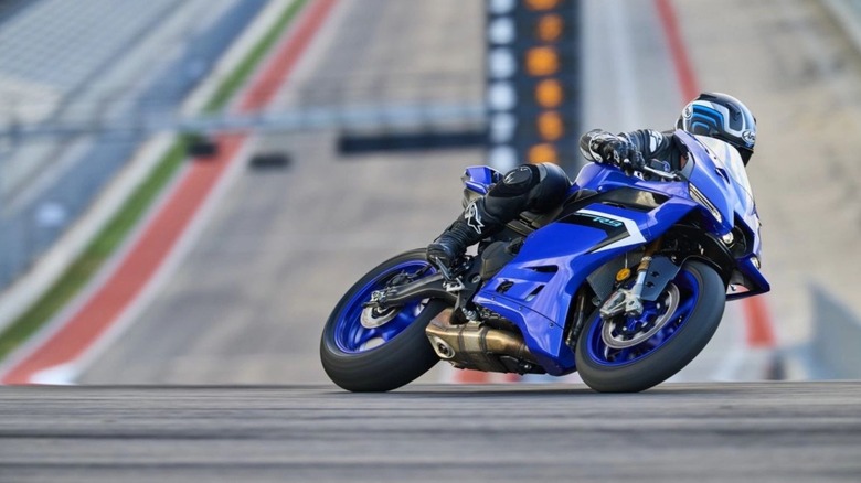 A biker turns a blue Yamaha R9 on a race track on a sunny day