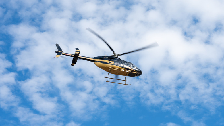 A helicopter flying against a cloudy sky.