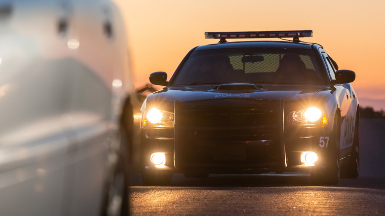 Police car parked behind car pulled over for speeding at sunset