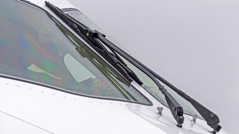 Aircraft cockpit windows with wipers on the windshield with rain drops