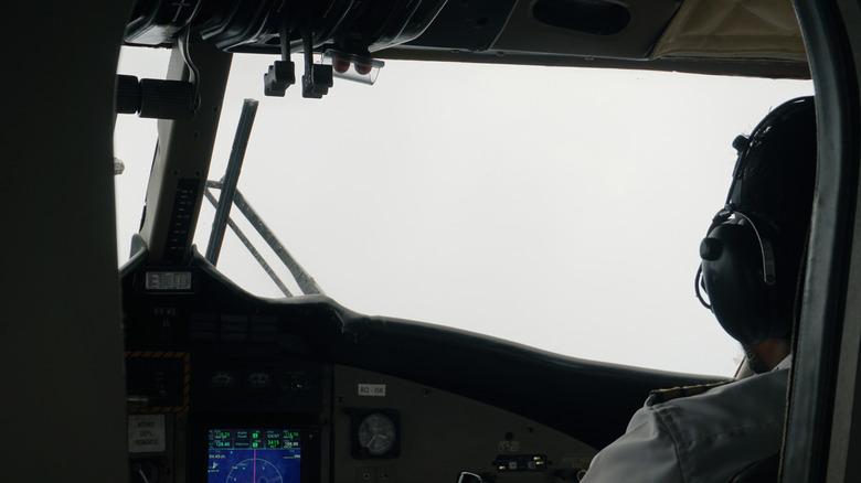 Pilot in the cockpit looking through windshield with poor visibility