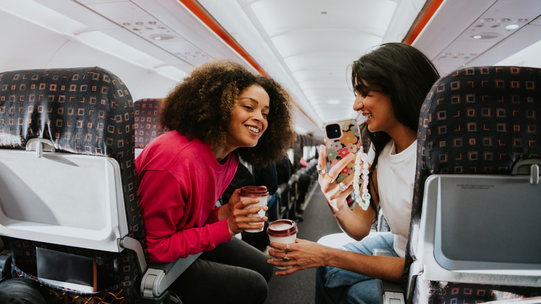 Two women looking at a smartphone while on an airplane