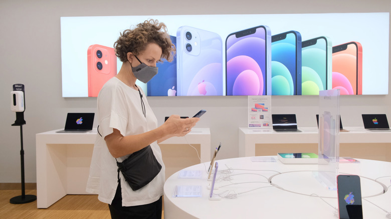 A man wearing mask looking at iPhone at Apple Store