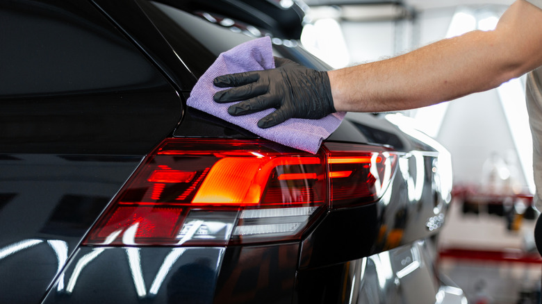 A Person Hand Detailing A Car With A Soft Towel