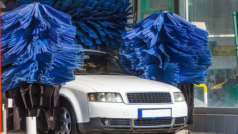 A White Car Navigating Through An Automatic Car Wash