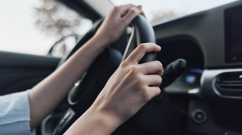 Person grabbing a car steering wheel.