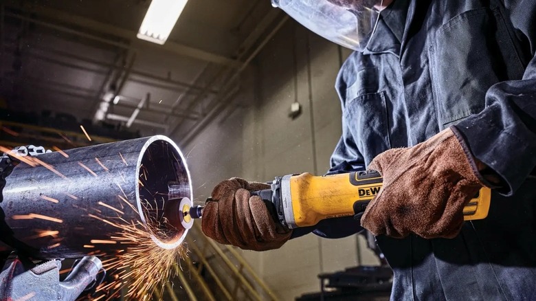 Using a corded DeWalt die grinder to work on a large metal pipe.