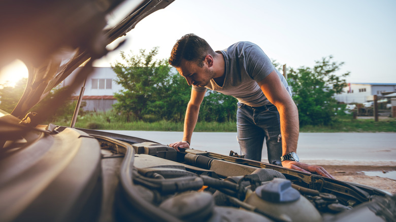 Owner checking their car's engine bay, wide angle shot