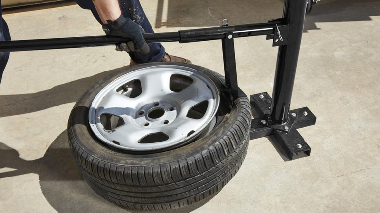 a person using the harbor freight pittsburgh manual tire changer on a passenger car  tire