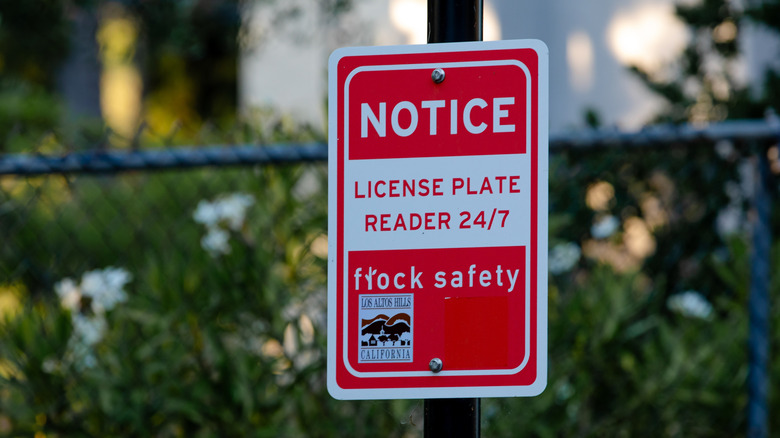 A red and white sign for Automatic License Plate Reader (ALPR) system by Flock Safety