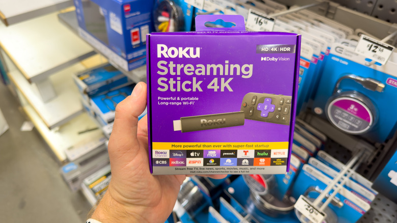 Someone holding a Roku Streaming Stick 4K box in the aisle of a store