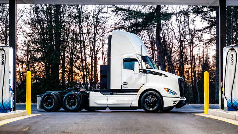 A Kenworth T680E electric semi truck parked between two PACCAR chargers.